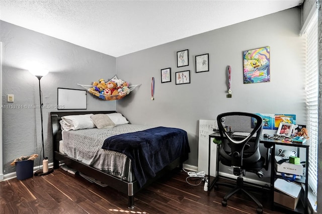 bedroom with a textured ceiling, baseboards, and wood finished floors