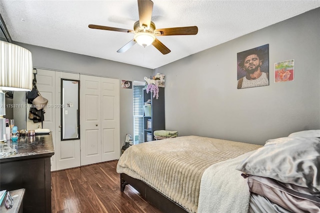 bedroom with dark wood-style floors, ceiling fan, a closet, and a textured ceiling