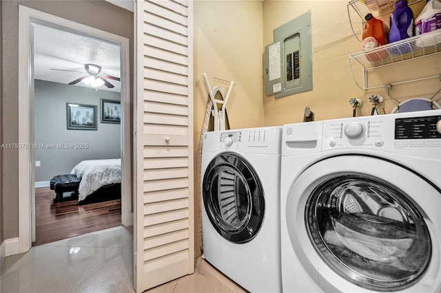 washroom with laundry area, electric panel, baseboards, washing machine and dryer, and light tile patterned flooring