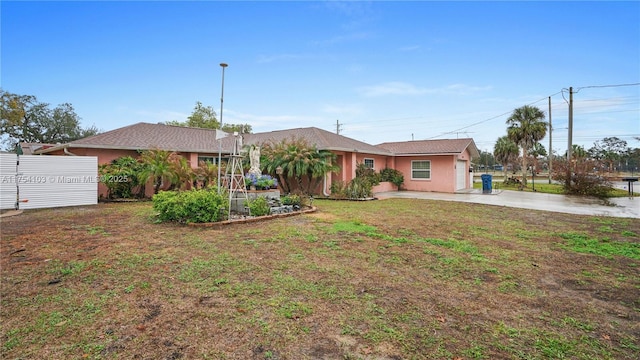 ranch-style home with stucco siding, fence, and a front yard