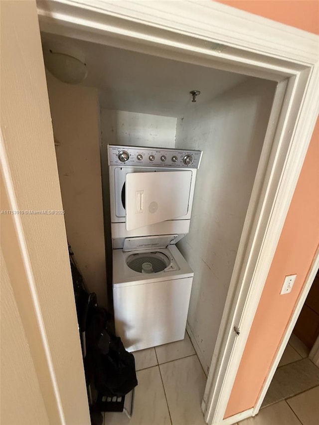 washroom with stacked washing maching and dryer, laundry area, and tile patterned floors