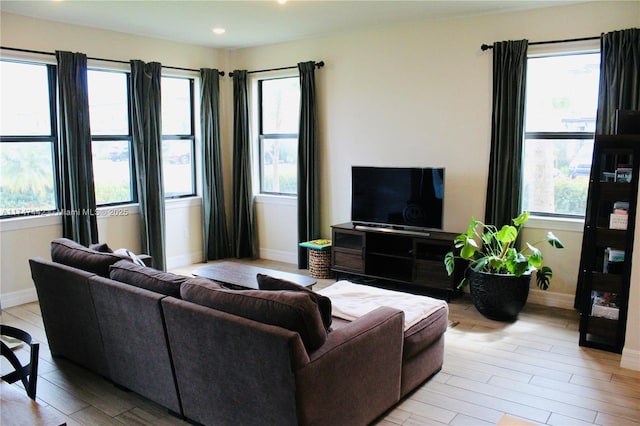 living room featuring a healthy amount of sunlight, light wood-style flooring, and baseboards