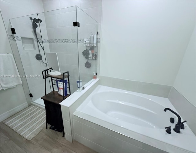 full bathroom featuring wood finished floors, a shower stall, and a bath