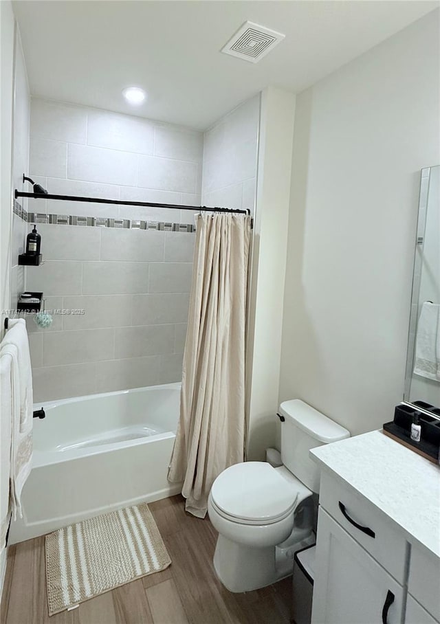 bathroom with shower / bath combo, visible vents, toilet, wood finished floors, and vanity