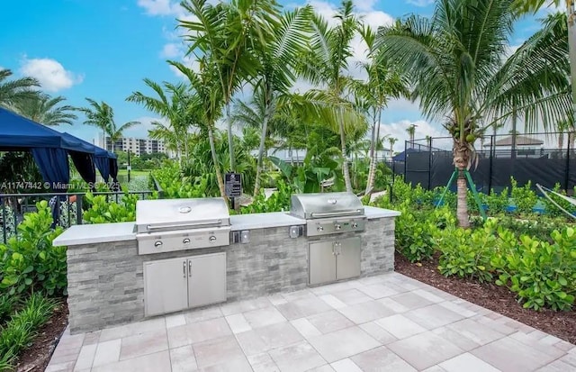 view of patio with a grill, fence, and an outdoor kitchen