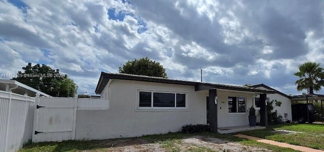 view of front of home featuring a gate, fence, and stucco siding