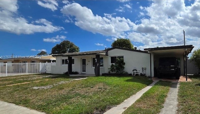 ranch-style home featuring a front yard, fence, an attached carport, and stucco siding