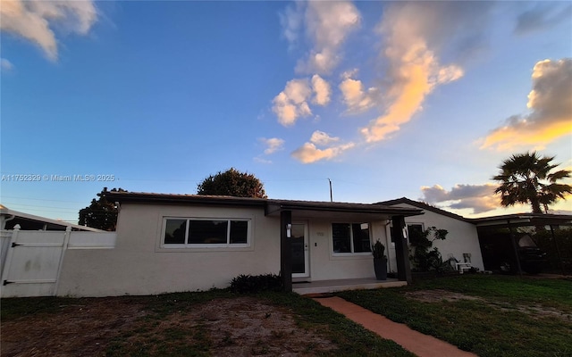 view of front of house featuring fence, a front lawn, and stucco siding