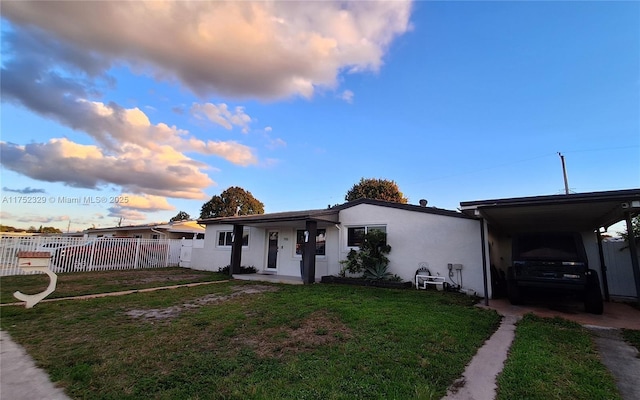 view of front of house featuring an attached carport, a front yard, fence, and stucco siding