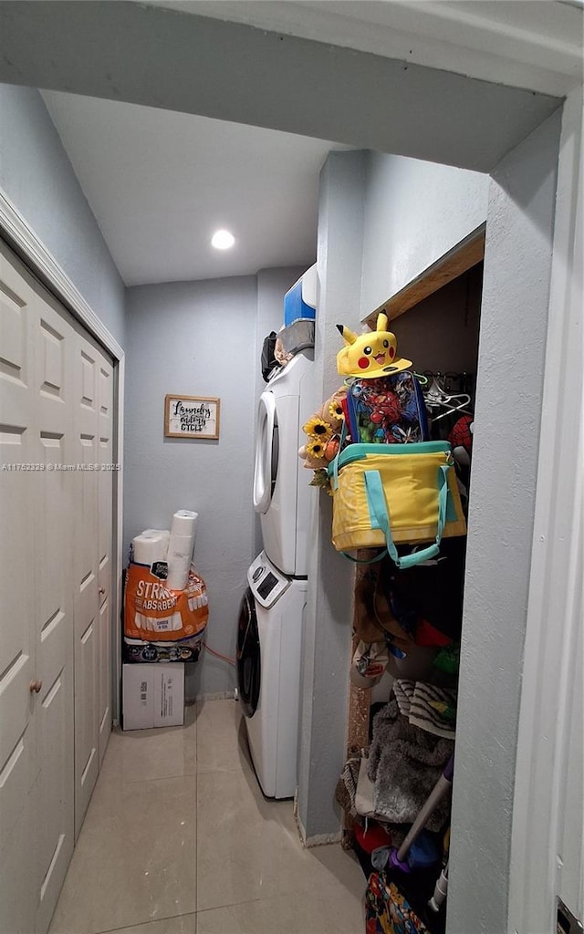 laundry area featuring stacked washer and clothes dryer, light tile patterned floors, and laundry area