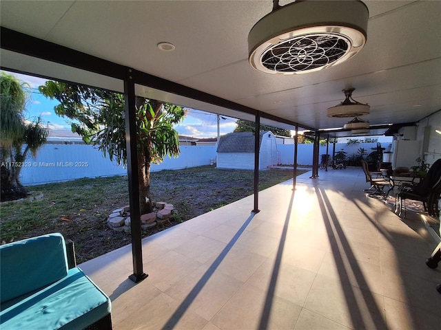 view of patio / terrace with an outbuilding, a storage unit, and fence