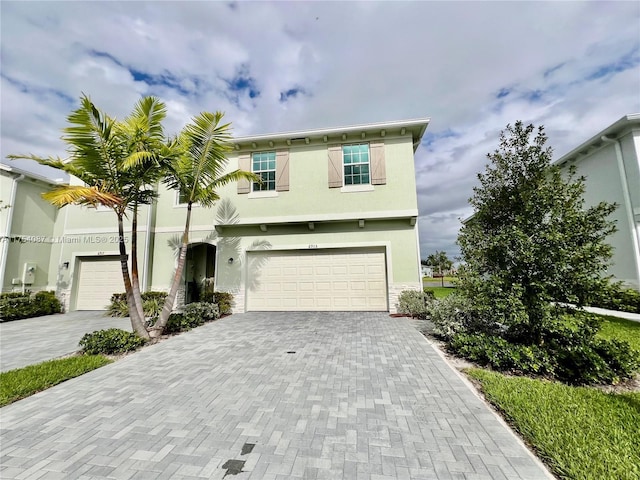 view of front of house featuring an attached garage, decorative driveway, and stucco siding