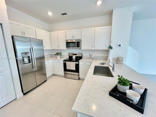 kitchen featuring appliances with stainless steel finishes, visible vents, a sink, and light stone countertops