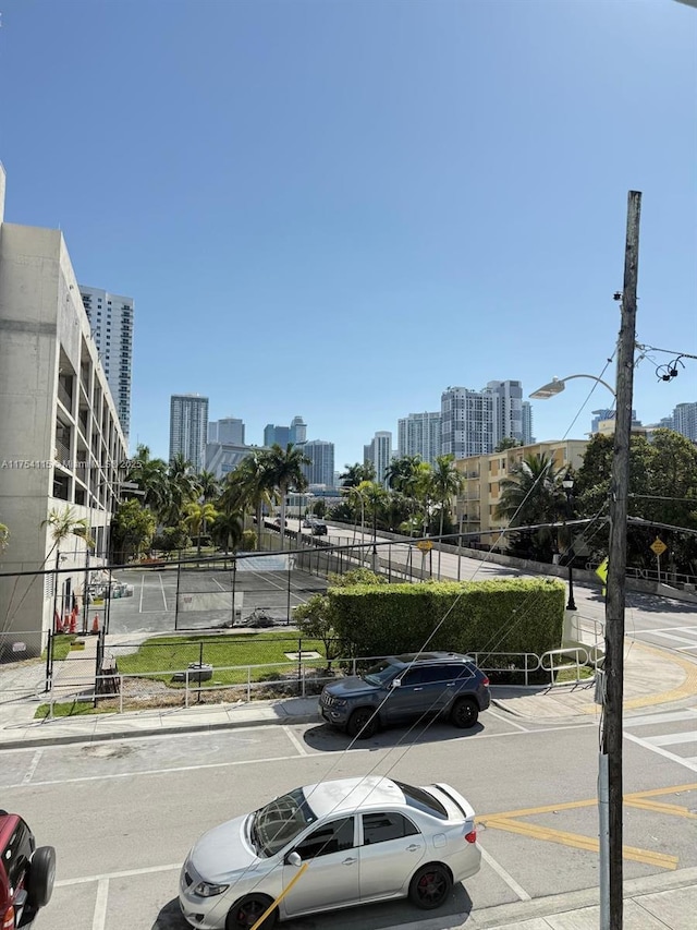 view of vehicle parking featuring a view of city and fence