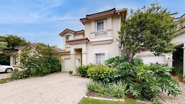 mediterranean / spanish-style house featuring a balcony, a tiled roof, and stucco siding