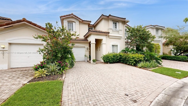 mediterranean / spanish-style home with a garage, a tile roof, decorative driveway, and stucco siding