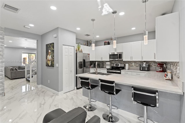 kitchen featuring marble finish floor, stainless steel appliances, light countertops, visible vents, and a kitchen breakfast bar