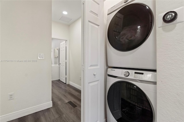 clothes washing area with recessed lighting, laundry area, baseboards, stacked washing maching and dryer, and dark wood finished floors