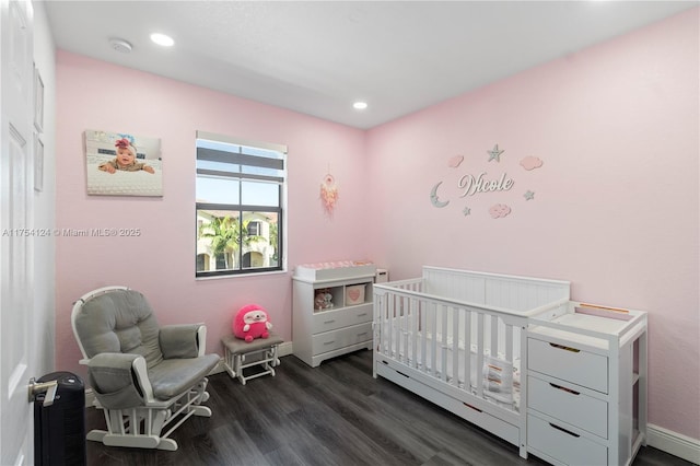 bedroom with a nursery area, baseboards, dark wood-type flooring, and recessed lighting