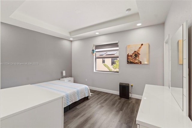 bedroom with dark wood-type flooring, recessed lighting, a raised ceiling, and baseboards