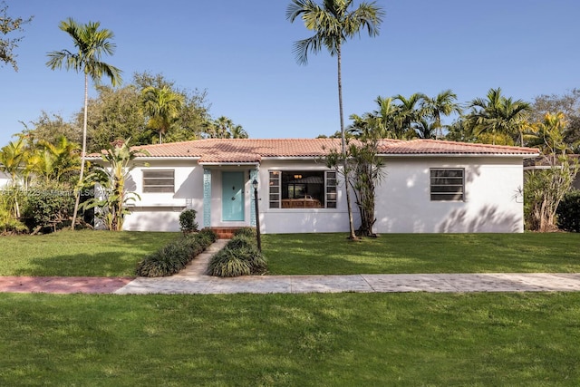 view of front of property featuring a front yard, a tile roof, and stucco siding