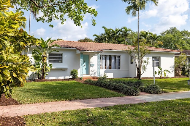 mediterranean / spanish home with stucco siding, a tiled roof, and a front yard