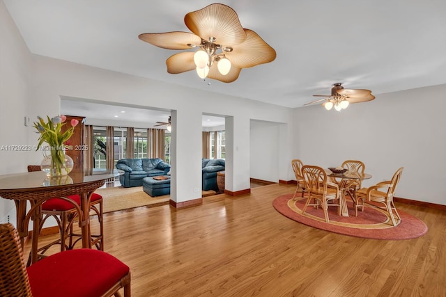 dining area with light wood-type flooring, baseboards, and a ceiling fan