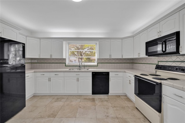 kitchen featuring black appliances, tile counters, tasteful backsplash, and a sink