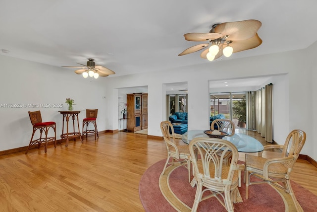 dining area with baseboards, a ceiling fan, and light wood-style floors