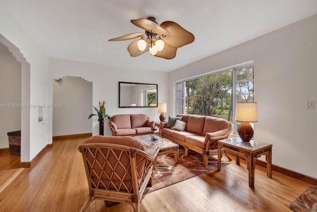 living area featuring ceiling fan, light wood-style flooring, and baseboards