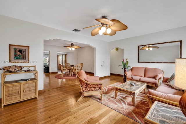 living area featuring a ceiling fan, light wood-style flooring, visible vents, and baseboards