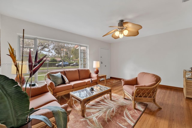 living room featuring a ceiling fan, visible vents, baseboards, and wood finished floors