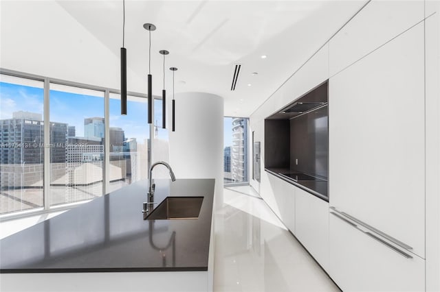 kitchen with dark countertops, modern cabinets, a sink, and white cabinets