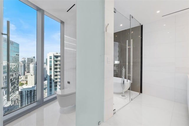 full bathroom featuring a view of city, floor to ceiling windows, toilet, tile patterned flooring, and a freestanding tub