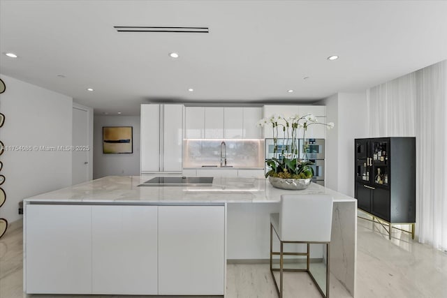 kitchen with black electric cooktop, a spacious island, a sink, white cabinets, and modern cabinets