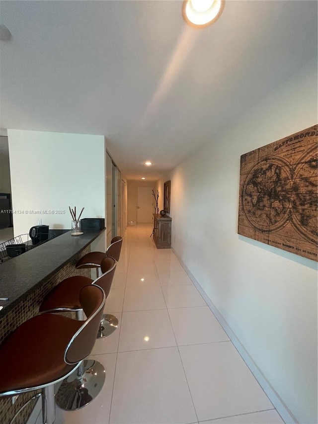 hallway featuring tile patterned flooring and baseboards