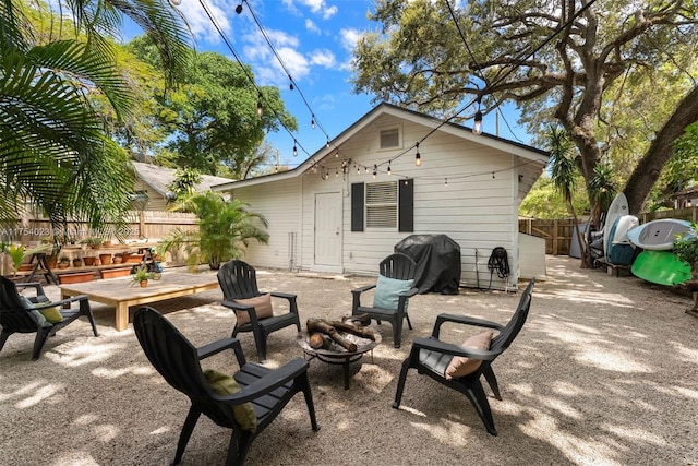 rear view of property featuring a fire pit, fence, and a patio