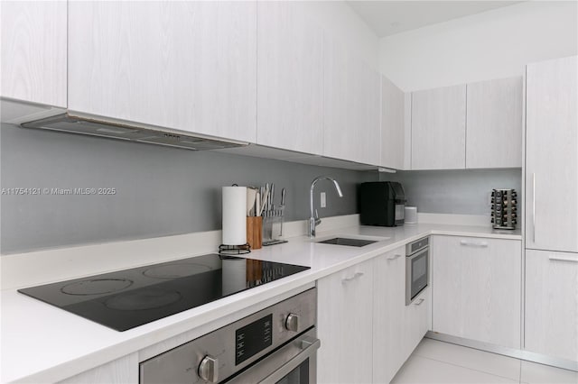 kitchen with light countertops, stainless steel oven, a sink, ventilation hood, and black electric cooktop