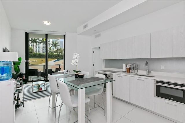 kitchen with black electric stovetop, oven, a sink, visible vents, and light countertops