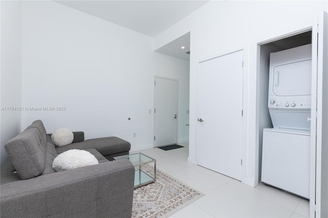 living room with light tile patterned floors, baseboards, and stacked washer / dryer