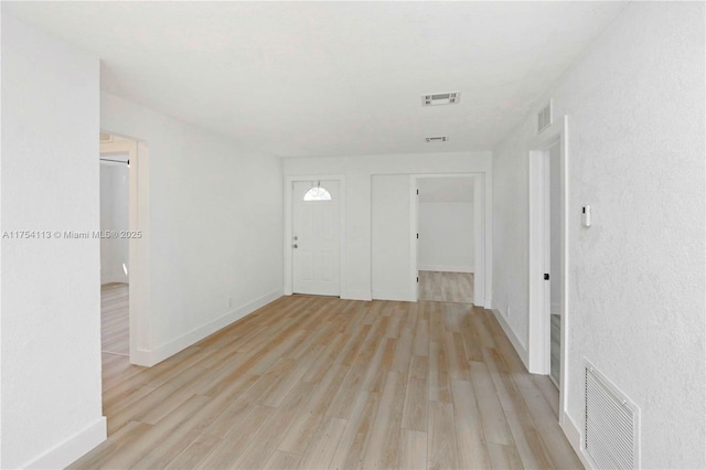 foyer entrance featuring baseboards, visible vents, and light wood-style floors