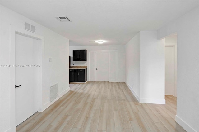 unfurnished room with light wood-type flooring, visible vents, and baseboards