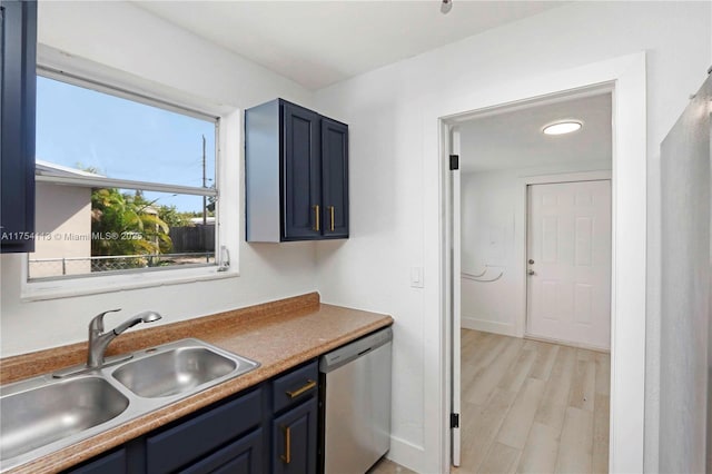 kitchen featuring light wood finished floors, a sink, blue cabinets, dishwasher, and baseboards