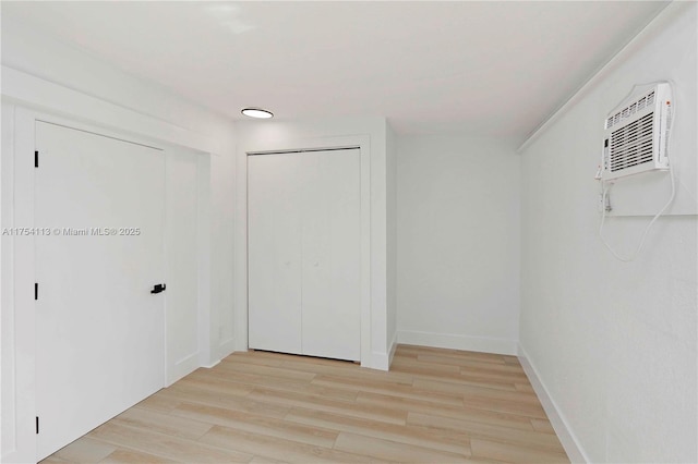 walk in closet with a wall mounted AC and light wood-type flooring