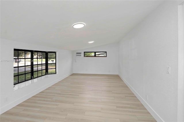 spare room with lofted ceiling, light wood-style flooring, and baseboards