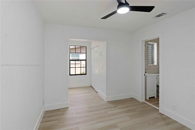 empty room featuring a ceiling fan, light wood-type flooring, visible vents, and baseboards