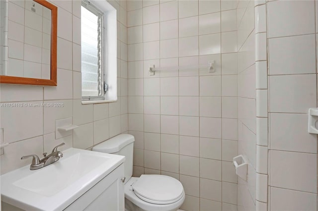 bathroom featuring toilet, tasteful backsplash, tile walls, and vanity