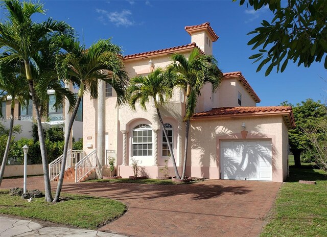 mediterranean / spanish-style house with a garage, a tiled roof, decorative driveway, and stucco siding