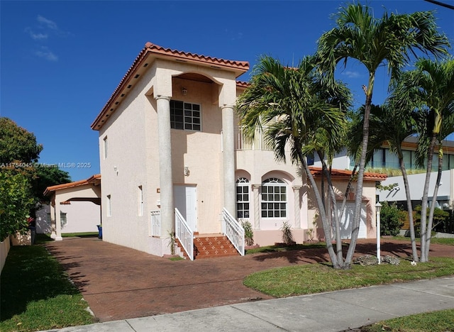 mediterranean / spanish house featuring driveway, a tile roof, a garage, and stucco siding