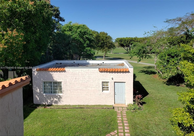 back of house with a lawn and stucco siding